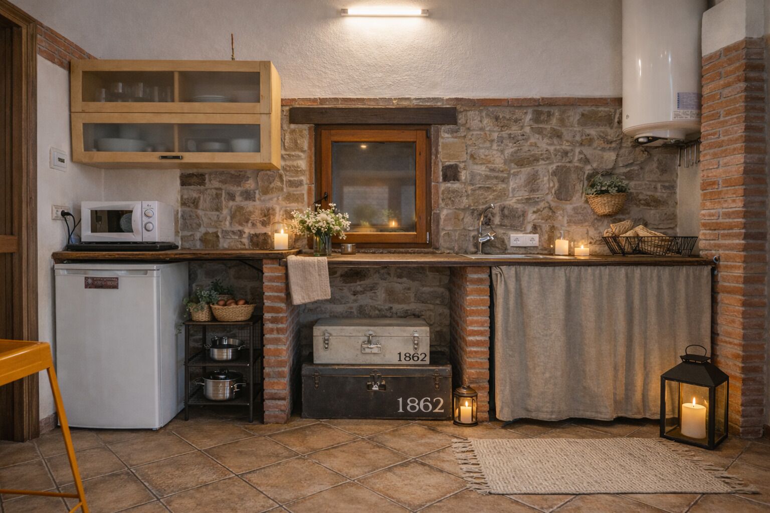 Een compact keuken met een stenen muur, een vintage koffer, een magnetron en een kleine koelkast.