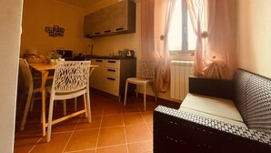 A compact living space with a kitchenette, a dining area, and a seating area with a sofa and a chair. - Da Nonna Pasqualina (Ciorlano)