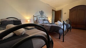 A bedroom with two beds, a wooden wardrobe, and a cross on the wall. - Da Nonna Pasqualina (Ciorlano)