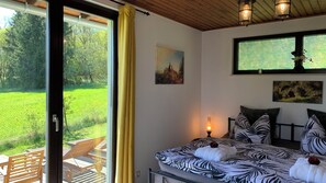 Ein Schlafzimmer mit Bett, einem Gemälde, einem Fenster und Blick auf ein grünes Feld.