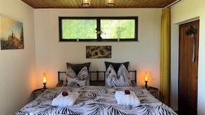 Ein Schlafzimmer mit einem Bett, zwei Nachttischen, einem Fenster und einer Tür.