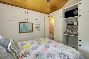 Ein Schlafzimmer mit einem Bett, einem Kleiderschrank, einem Fernseher und Bildern an der Wand.