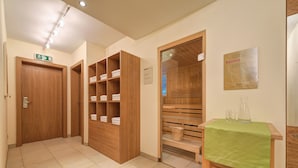 Habitación de hotel con muebles de madera, una mesa verde y un letrero de sauna en la pared.