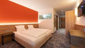 Una habitación de hotel moderna con una cama grande, una mesita de noche, un televisor en la pared y una pared decorativa de madera.