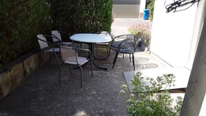 Un patio esterno con un tavolo rotondo e quattro sedie.