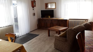 Un soggiorno con un armadio in legno, televisore, divano e tavolo da pranzo.