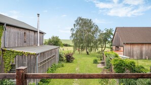 A rustic barn with a chimney, surrounded by a lush green landscape and a clear blue sky. - Nice apartment in Am Salzhaff with WiFi (Am Salzhaff)