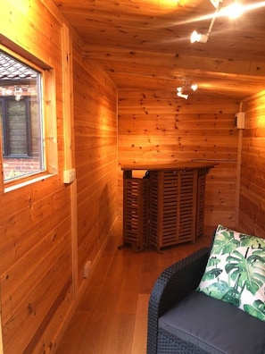 Cozy cabin interior with a bench, wicker sofa, and window with blinds.