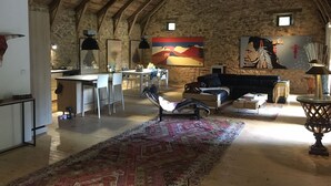 Ein rustikales Interieur mit einer Steinwand, einem Essbereich, einer Couch und einem gemusterten Teppich.