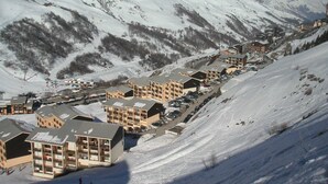 A snow-covered mountain town with multiple multi-story buildings, likely hotels, arranged along a hillside. - Functional studio in Menuires, close to slopes, balcony (Les Menuires)