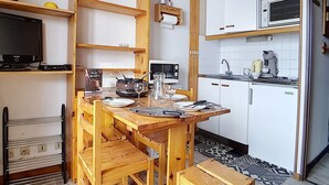 A compact kitchen with a wooden table, chairs, a microwave, and a sink. - Functional studio in Menuires, close to slopes, balcony (Les Menuires)
