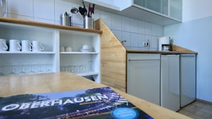 Une cuisine moderne avec des meubles blancs, un plan de travail en bois et une machine à café.