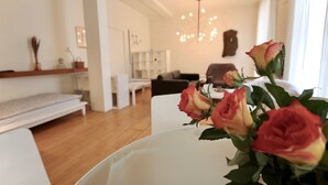 Un salon moderne avec un canapé blanc, une table basse ornée de roses et un lustre.