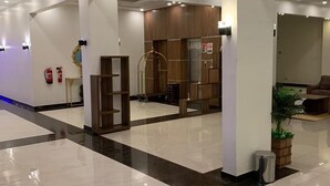 Eine großzügige Lobby mit glänzendem Boden, einem Empfangstresen und einer Sitzecke.