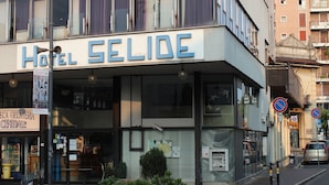 Um hotel chamado "Hotel Selide", com fachada moderna, janelas amplas e um caixa eletrônico visível na parte externa.