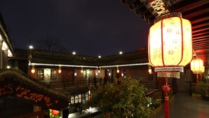 A traditional building with a tiled roof and illuminated lanterns. - True Go Hotel (Beijing)