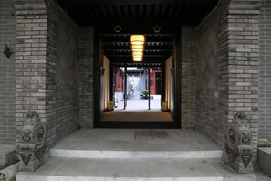 A traditional entrance with a brick wall, a wooden ceiling, and a lantern. - True Go Hotel (Beijing)