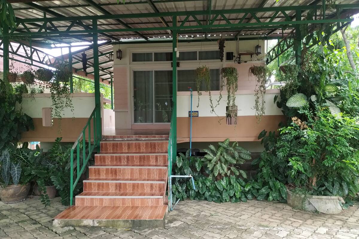 Uma área externa coberta com uma escada de madeira que leva à entrada de um edifício.