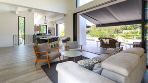Een ruime woonkamer met een grote bank, een salontafel, en een eethoek met stoelen en een tafel.