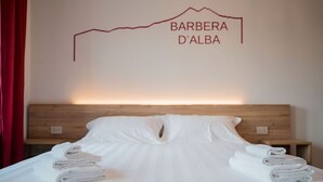 A hotel room with a neatly made bed, a wooden headboard, and a wall-mounted sign that reads "BARBERA D'ALBA". - Vino e Turismo (Cervasca)