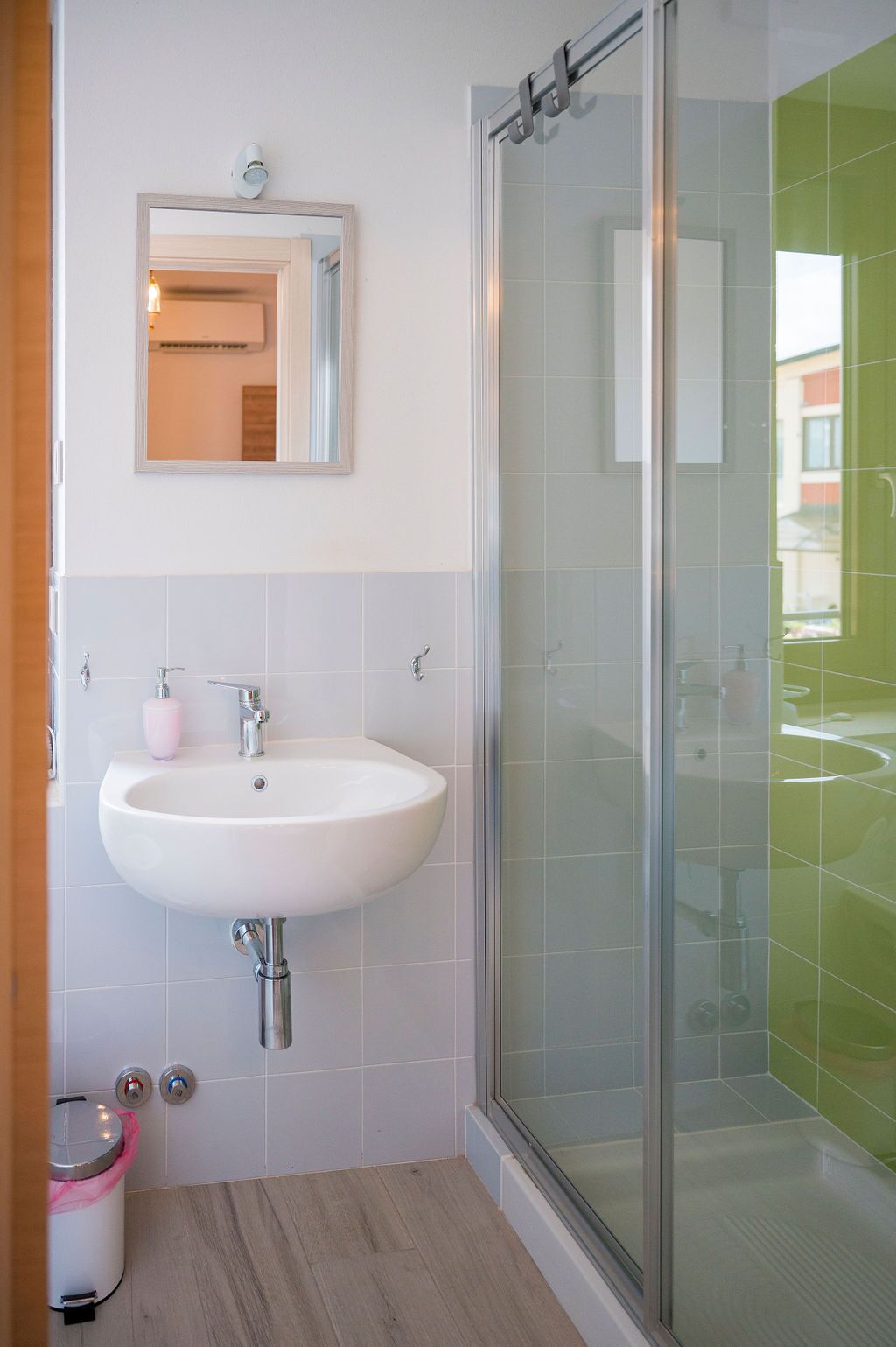 A modern bathroom with a white sink, a glass shower enclosure, and a mirror above the sink.