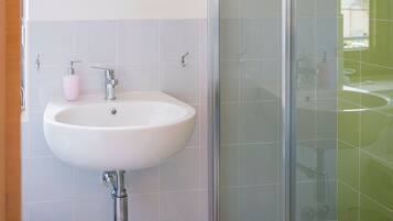 A modern bathroom with a white sink, a glass shower enclosure, and a mirror above the sink.