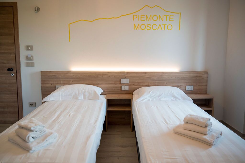 A hotel room with two beds, wooden headboards, and a wall-mounted light.