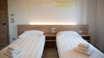 A hotel room with two beds, wooden headboards, and a wall-mounted light.