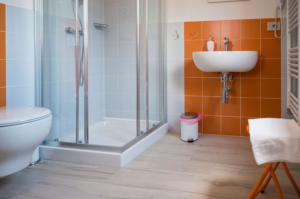Ein Badezimmer mit einer Duschkabine, einem weißen Waschbecken und einer Toilette.