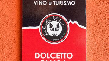 Une boîte noire et rouge portant la mention « DOLCECCITO D’ALBA », avec un logo et le texte « VINO e TURISMO ».