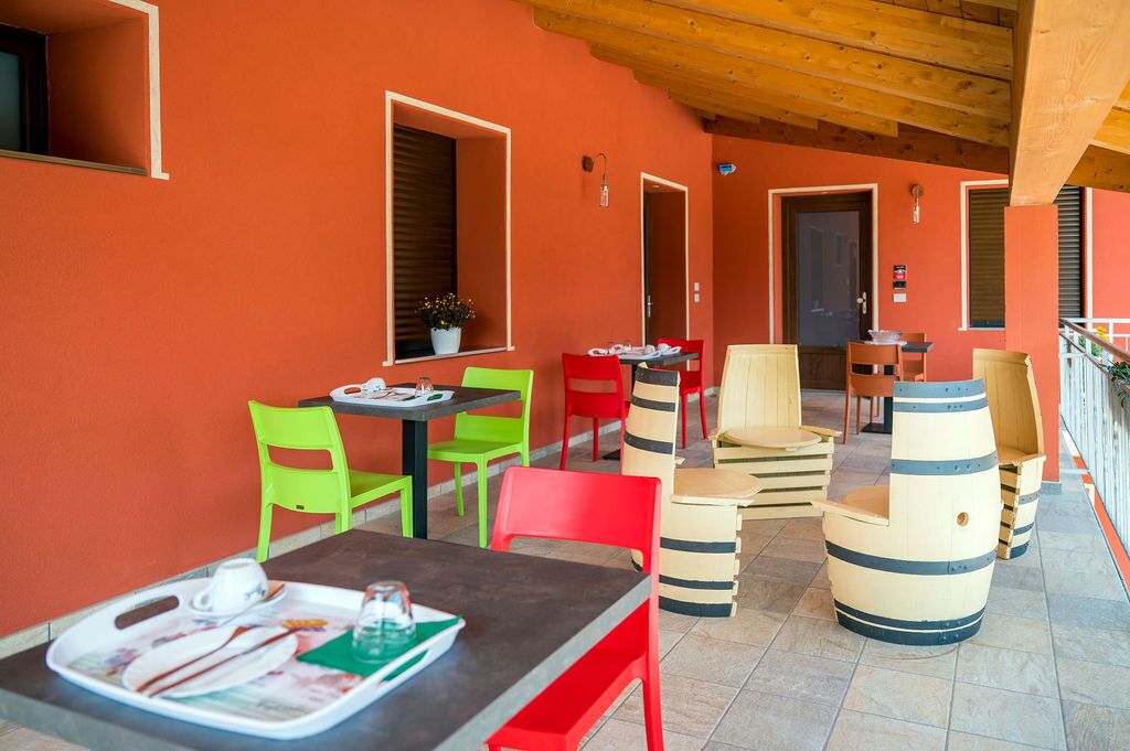 A dining area with red walls, wooden ceiling, and colorful chairs.