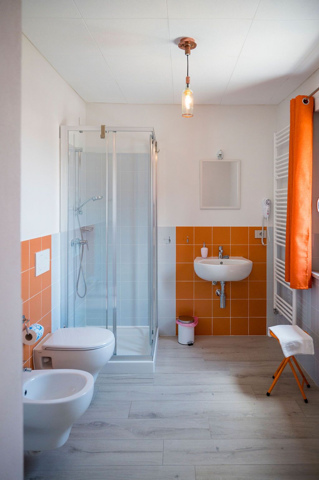 A bathroom with a glass shower enclosure, a white sink, and a bidet.