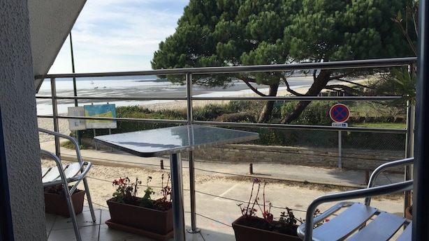 A balcony with a table, chairs, and potted plants. A no parking sign is visible.