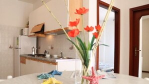 Ett modernt kök med vita skåp, en inbyggd ugn och en bänkskiva dekorerad med en vas med blommor och sjöstjärnor.