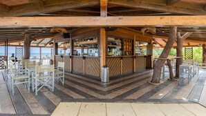 Un área de bar al aire libre con vigas de madera, barra y asientos.