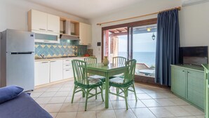 Cocina compacta con comedor, refrigerador, estufa y televisor.