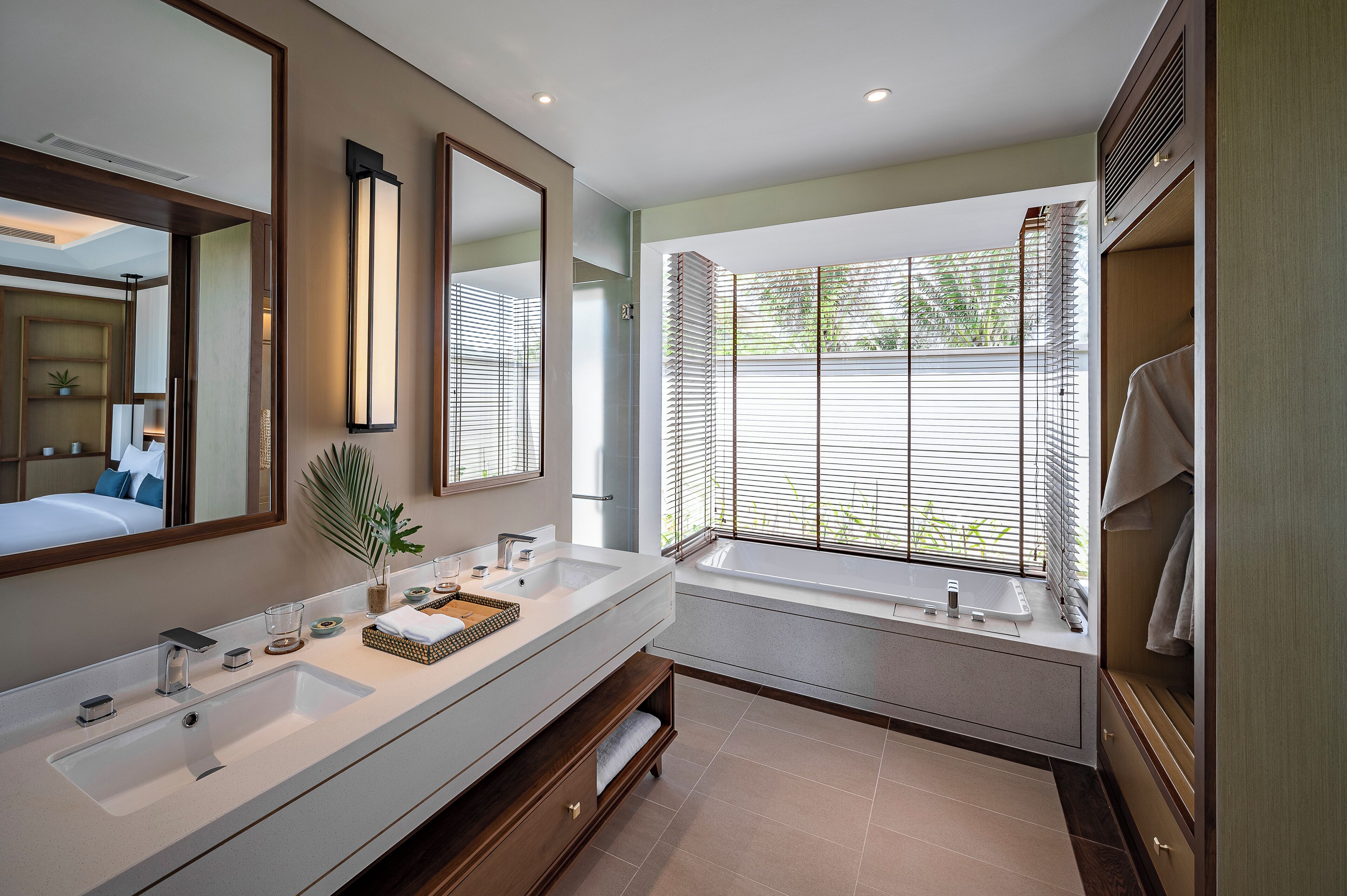 Un baño moderno con un espejo grande, una bañera y un tocador con lavamanos.