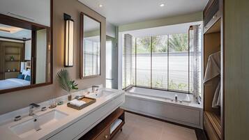 Un baño moderno con un espejo grande, una bañera y un tocador con lavamanos.