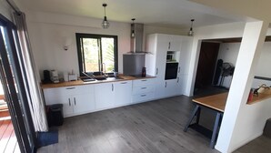 A modern kitchen with white cabinets, a wooden countertop, and a large window. - KAZ VILLELE 4 STARS Pool / Jacuzzi (Saint Gilles les hauts)