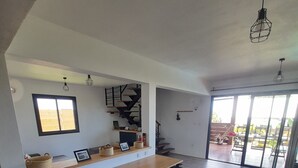 A spacious kitchen with a wooden bench, a built-in shelf with baskets, and a staircase leading to an upper level. - KAZ VILLELE 4 STARS Pool / Jacuzzi (Saint Gilles les hauts)