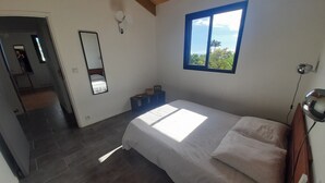 A bedroom with a bed, a window, a mirror, and a ceiling fan. - KAZ VILLELE 4 STARS Pool / Jacuzzi (Saint Gilles les hauts)