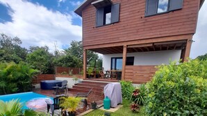 A two-story house with a patio, a swimming pool, and lush greenery. - KAZ VILLELE 4 STARS Pool / Jacuzzi (Saint Gilles les hauts)