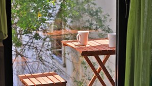 A wooden table with two white textured mugs on it, positioned near a window with a view of trees and a building. - Zeytin Hotel (Kas)