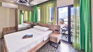 A hotel room with a large bed, a bedside table, a mirror, and a view of the outside. - Zeytin Hotel (Kas)