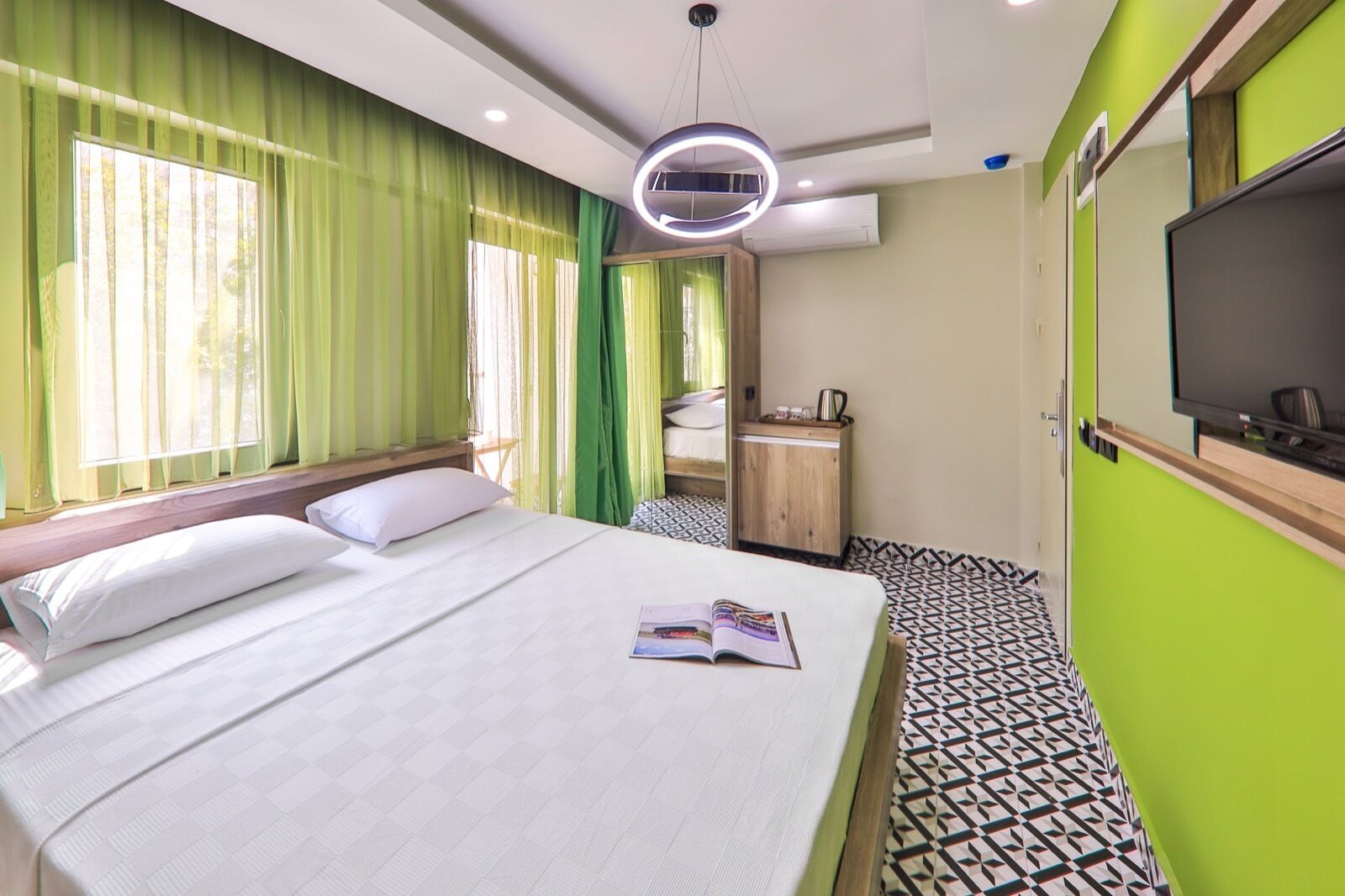 Een hotelkamer met een groot bed, een televisie en een klein bureau.