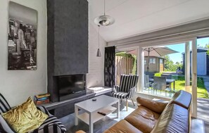 Ein modernes Wohnzimmer mit Kamin, einer Couch, einem Couchtisch und einem Essbereich mit Gartenmöbeln.