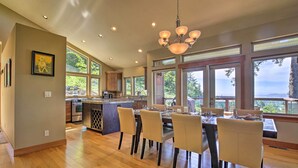 Een ruime keuken met een groot eiland, houten vloeren en een eethoek met stoelen en tafels.