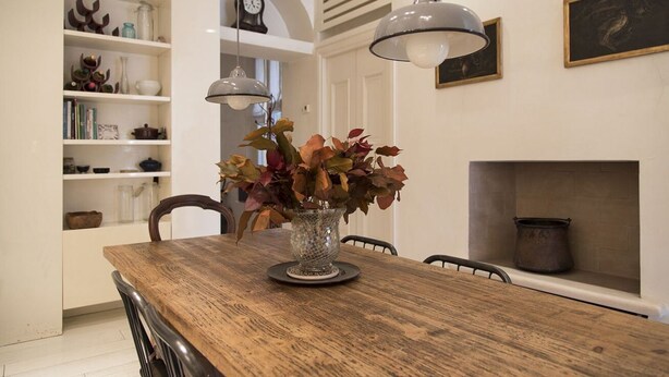A dining area with a wooden table, a vase with flowers, pendant lights, a bookshelf, and a fireplace. - Charming apartment 2 bdrs in Brera district (Milano)
