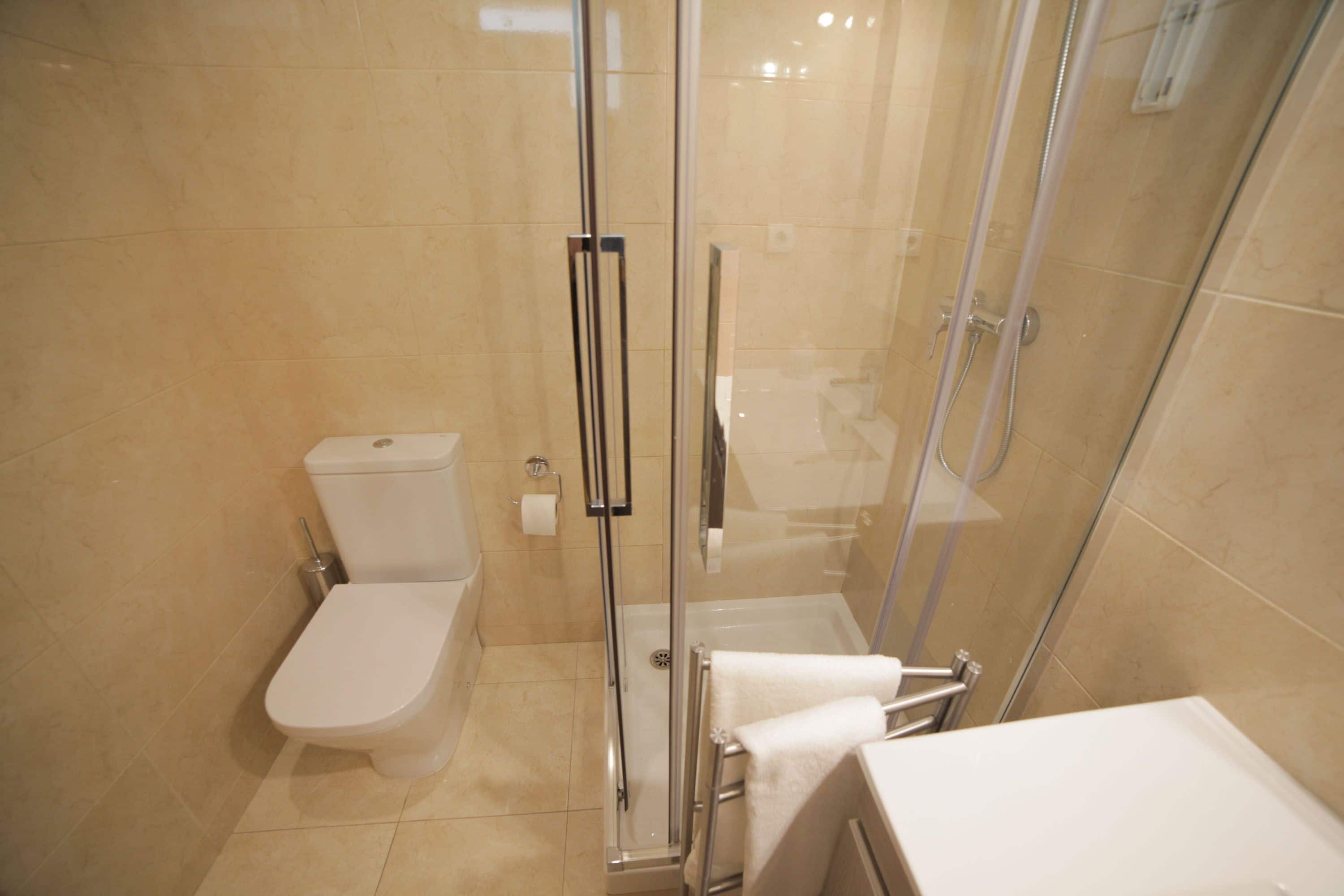 Un bagno moderno con cabina doccia in vetro, un water e un lavandino.