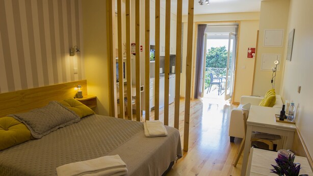 A bedroom with a bed, bedside table, and a view of a balcony. - Cedofeita Back Garden (Porto)